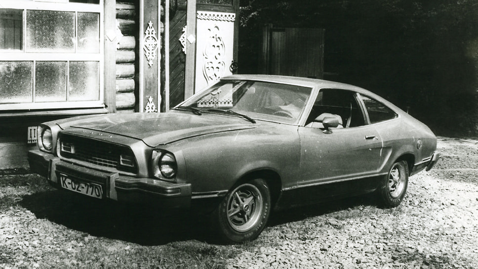 Принадлежавший Луи американский Ford Mustang 1976 года выпуска на фоне гаража в Баковке, построенного в русском стиле. На автомобиле номера, говорящие о том, что машина принадлежит корреспонденту западногерманского издания