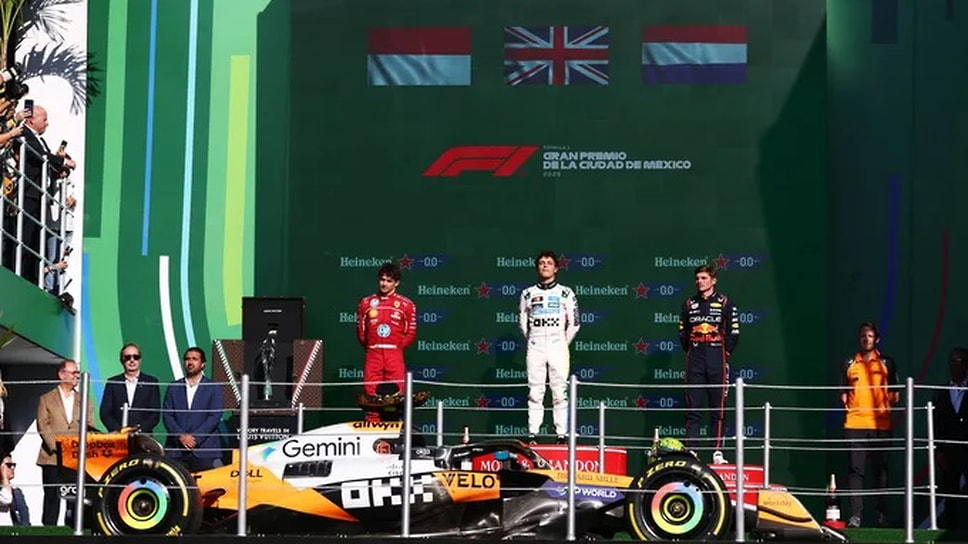 Специальный лифт поднимает машину победителя Гран-при Мехико прямо на мостик подиума, который разделили Леклер, Норрис и Ферстаппен (слева направо)